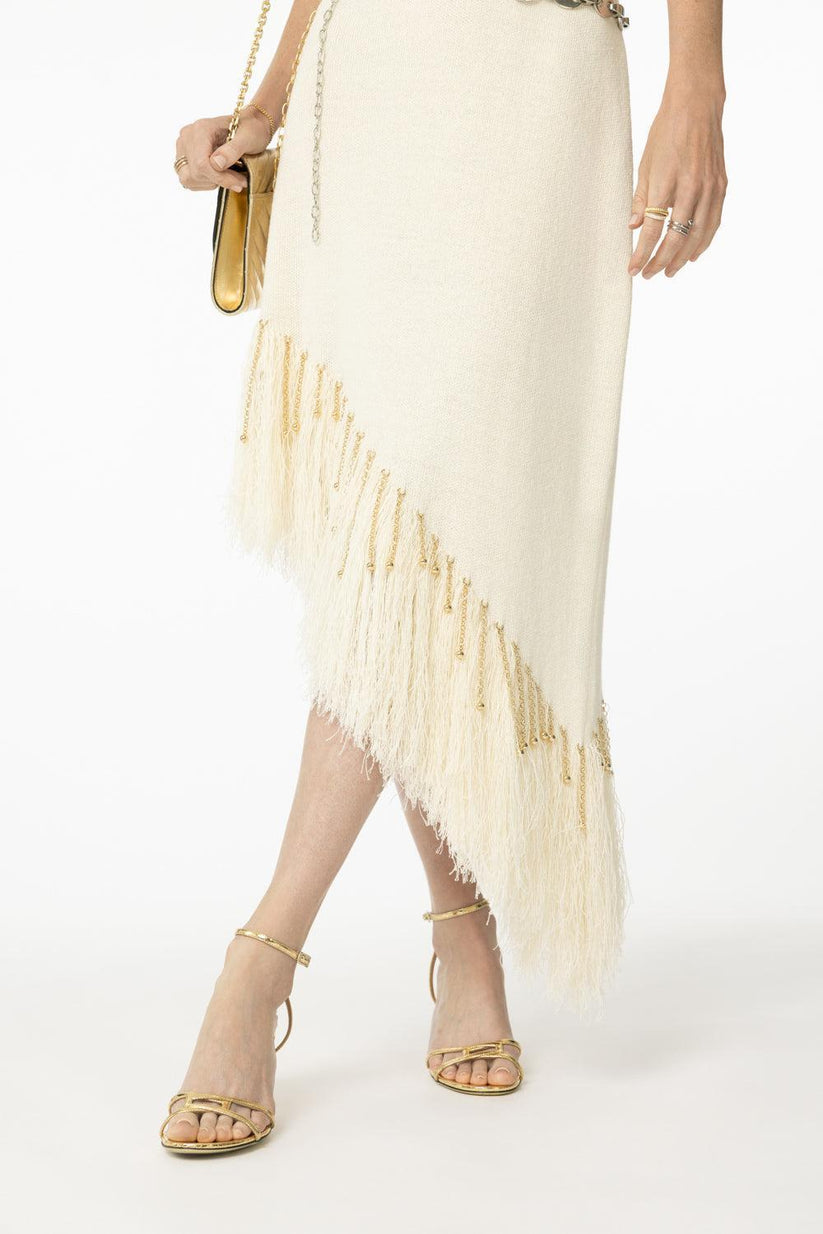 a woman wearing a white skirt and gold heels