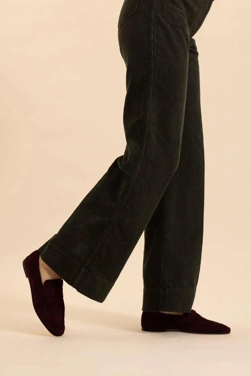 a person's legs in black pants and red shoes